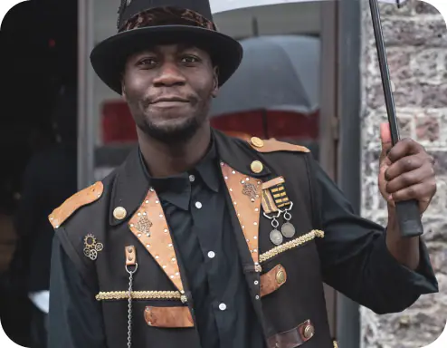 Smiling man in steampunk-style jacket and hat holding an umbrella
