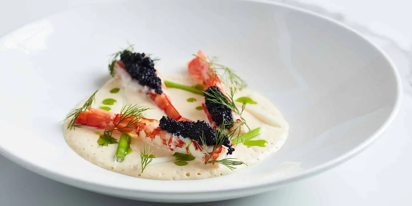 Gourmet prawns topped with black caviar, herb oil and foam