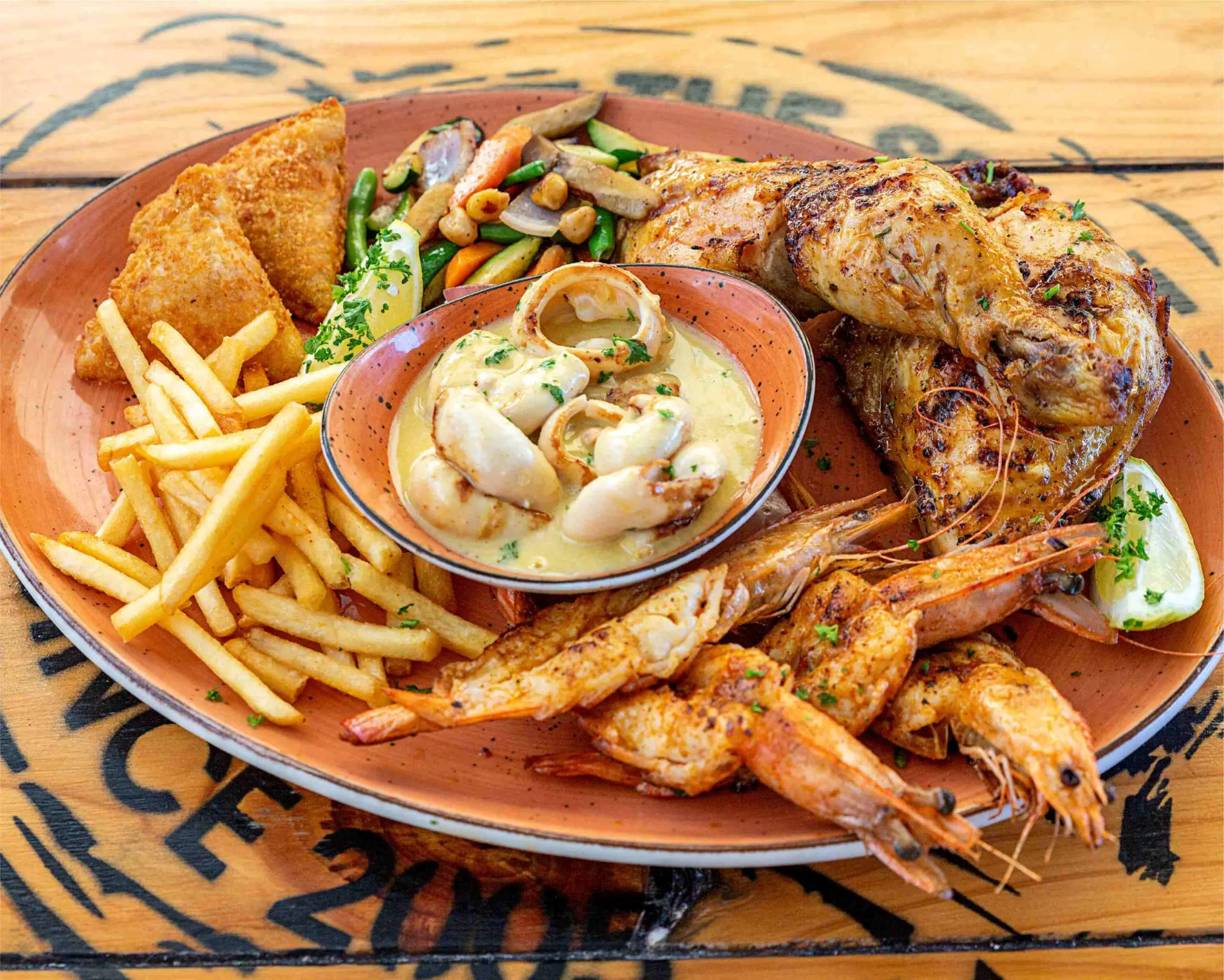 Mixed seafood and roasted chicken platter with fries and creamy shellfish sauce