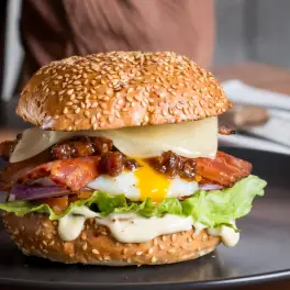 Sesame-seed burger with melted cheese, bacon, runny egg, lettuce, mayo
