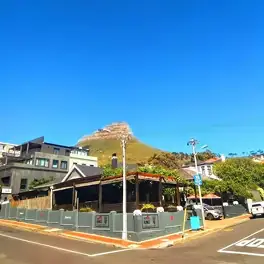 Corner outdoor café with fenced patio and mountain peak under bright blue sky