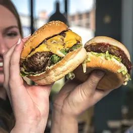 Two hand-held burgers, one cheeseburger with melted cheddar and lettuce