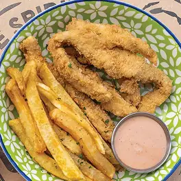 Breaded chicken tenders with fries and pink dipping sauce in green patterned bowl