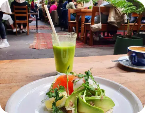 Brunch plate with sliced avocado, tomato and microgreens, green juice and coffee