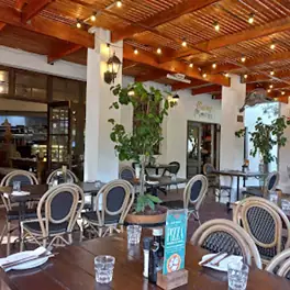 Open-air restaurant dining area with wooden beams, string lights and rattan chairs