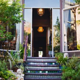 Mosaic-tiled entrance steps leading to open doorway with chandelier and plants