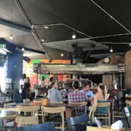 Customers dining and chatting in a casual bar-restaurant with colorful mural