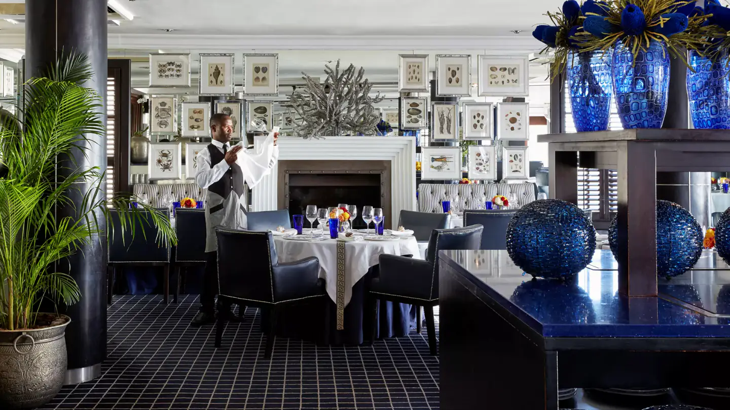 Elegant restaurant dining room with white‑clothed tables and waiter