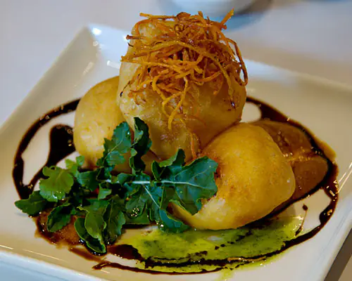 Three fried croquettes with salad greens and balsamic glaze