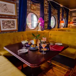 Cozy banquette with cocktails and small plates by porthole windows
