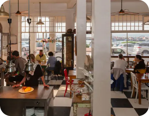 Busy seaside café interior with diners and server behind counter