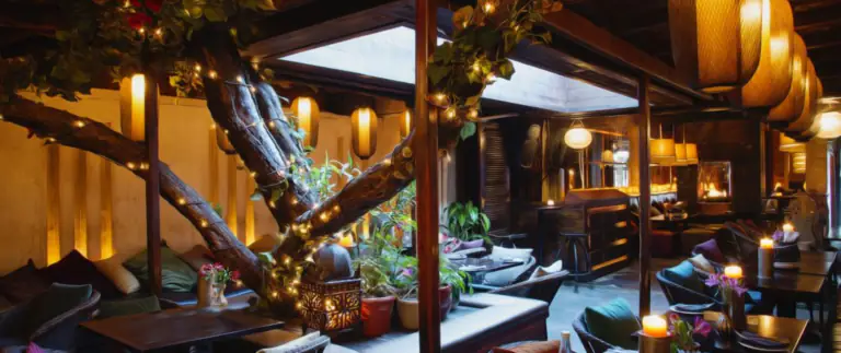 Cozy dimly lit restaurant interior with central tree trunk wrapped in string lights and candles