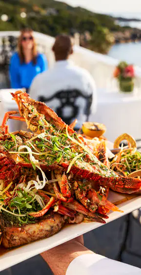 Platter of cooked lobsters garnished with herbs on outdoor dining terrace