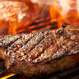 Sizzling grilled steaks searing over open flames on a barbecue grill